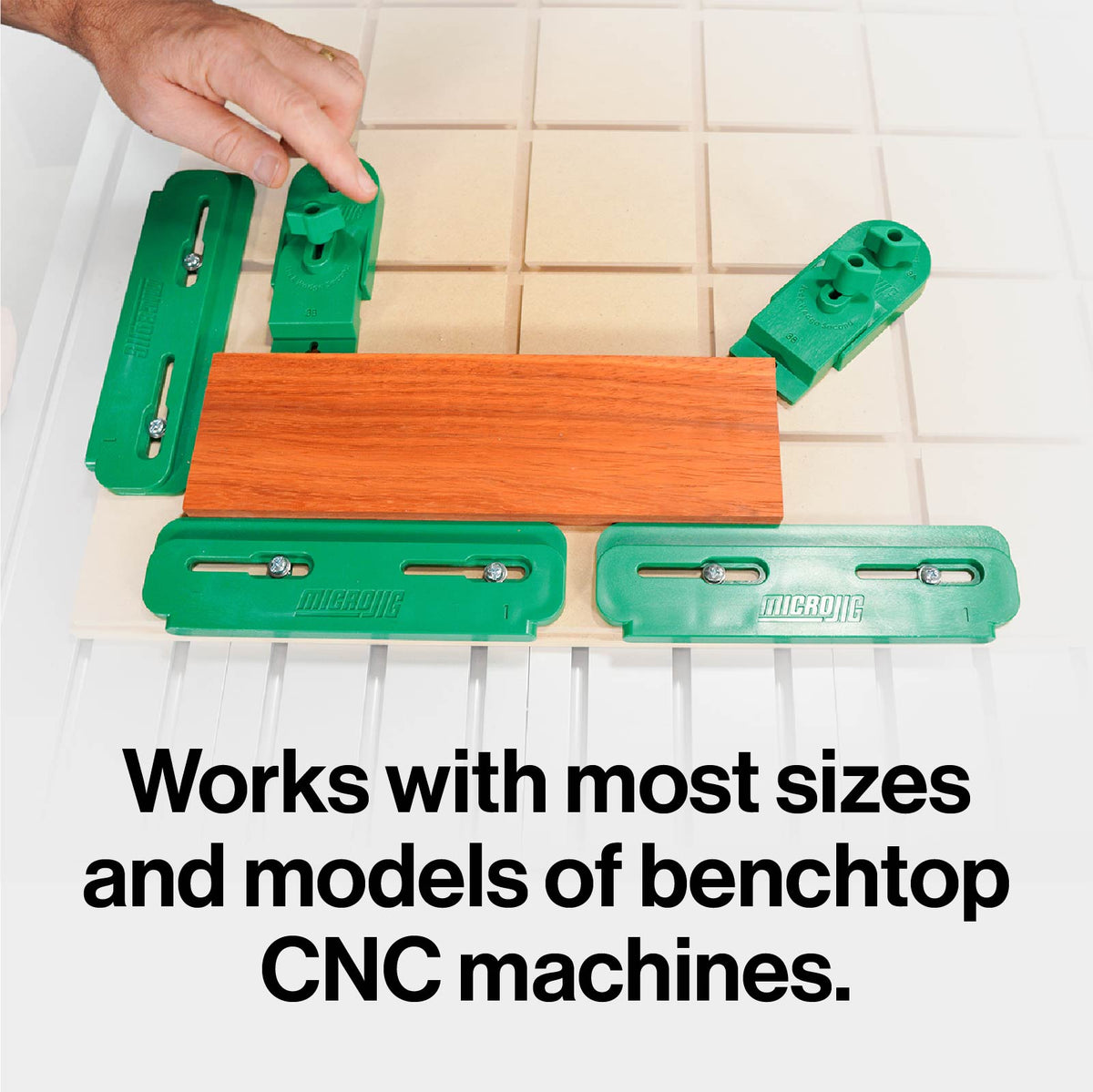 CNC clamping kit with green hold-down clamps securing wood on a benchtop CNC machine.