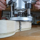 Woodworker using a plunge router with straight bit to shape hardwood on workbench