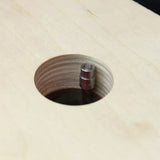 Close-up of a woodworking router bit cutting a clean hole in plywood