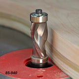 Spiral flush trim router bit shaping wood edge on a router table, close-up view.