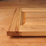 Close-up of unfinished raised panel cabinet door with decorative wood profile on workbench