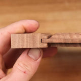 Hand holding interlocking wooden boards with tongue and groove joint for woodworking projects