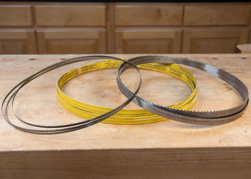 Bandsaw blades and yellow-backed wood cutting saw blades on a workshop table