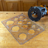 Acrylic circle and radius cutting template with various hole sizes on a woodworking bench next to a router tool.