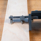 Digital marking and mortise gauge measuring a wooden board on a workbench