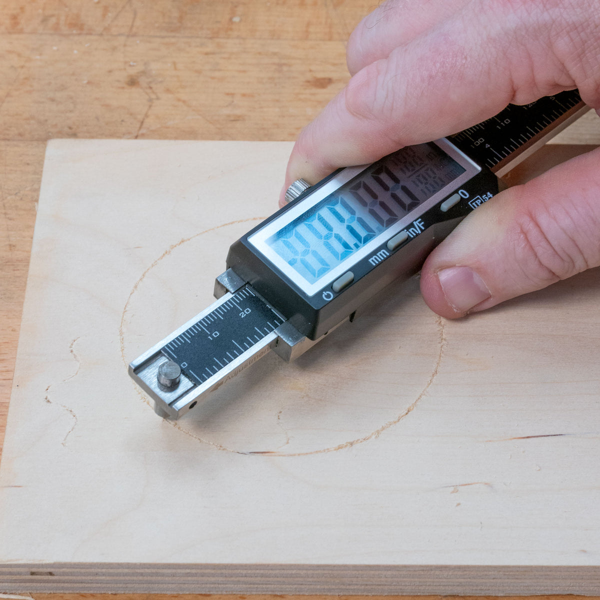 Hand using digital marking gauge on wood for precise measurement and layout work