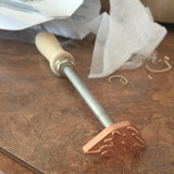 Woodburning branding iron with wooden handle on a workshop table