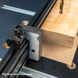 Drill press fence with flip stop attached, guiding a wood block on a workbench