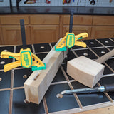 Woodworking clamps securing lumber on a workbench with mallet and chisel nearby