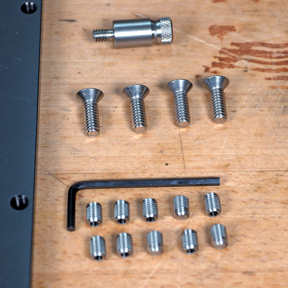 Router table hardware kit with screws, set screws, dowel pin, and hex key on wood surface
