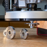 Slot cutter arbor attached to router in use on wood, with bearings on a workbench