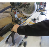 Person using a saw push stick to guide wood on a miter saw for safe woodworking cuts