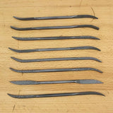 Set of eight curved woodworking rasps on a wooden surface for wood carving and detailing