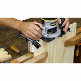 Woodworker using a router and dovetail jig to cut joinery in a wood board on a workbench
