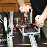 Woodworker using a joinery jig with clamps on a router table for precise woodworking cuts.