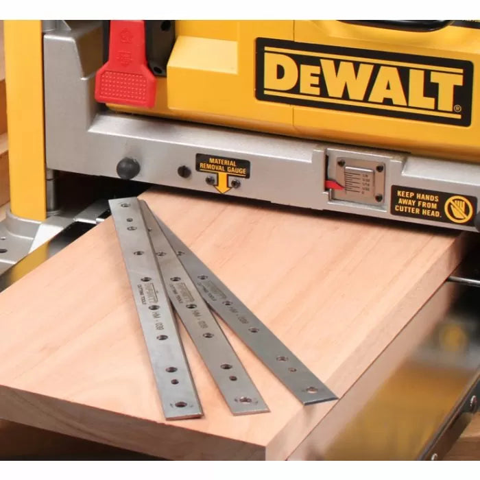 Planer knives set on wood board in front of a DeWalt woodworking planer