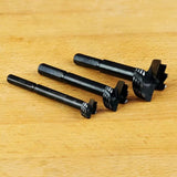 Set of three woodworking Forstner drill bits on a wooden surface