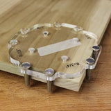 Clear acrylic woodworking jig for routing corners on a wood board, placed on workbench
