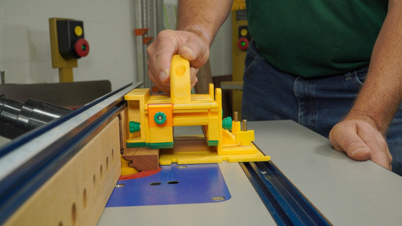 Woodworker using a yellow router table push block for precise, safe woodworking cuts