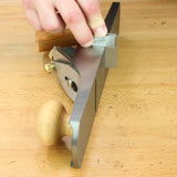 Woodworker checking flat sole of metal hand plane on workbench with precision tool
