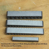 Metal drill blocks with bore alignment marks on wooden surface, woodworking tools.