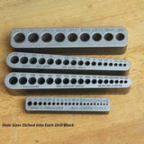 Assorted metal drill guides and blocks with etched hole sizes on wood surface