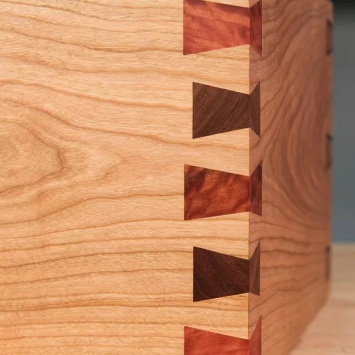 Close-up of a wooden box with decorative dovetail joints, showcasing fine woodworking craftsmanship.