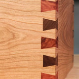 Close-up of a wooden box with decorative dovetail joints, showcasing fine woodworking craftsmanship.