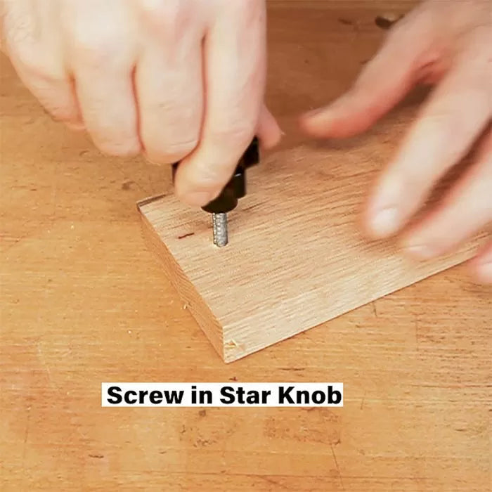 Hand screwing in star knob into wood block on workbench for woodworking project