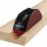 Handheld sanding block tool smoothing a wooden molding groove