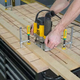 Woodworker using a router with jig system to cut grooves in a workbench top