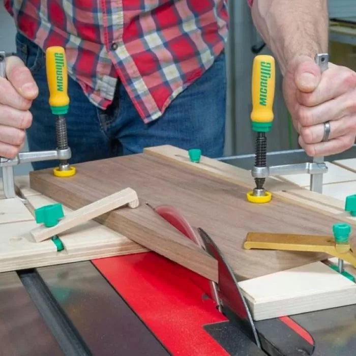 Woodworker using matchfit jig system and clamps on table saw for precise cutting.