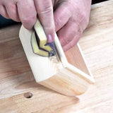 Hand sanding inside corner of a wooden box with a precision sanding block on workbench