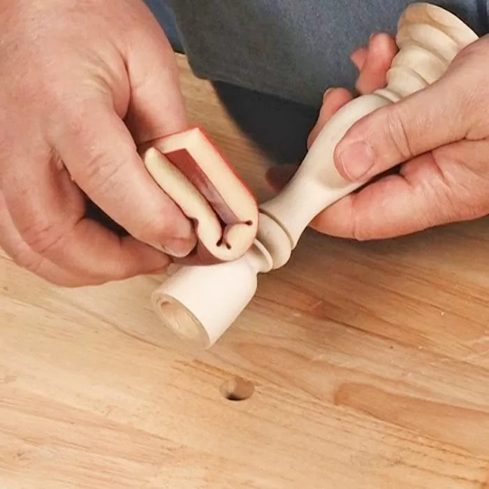 Hand sanding intricate wood spindle on workbench with flexible sanding tool