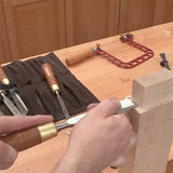 Woodworker using a chisel to refine a mortise and tenon joint on a workbench