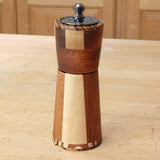 Handcrafted wooden pepper mill with segmented wood design on a workshop table