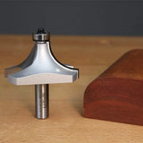 Roundover router bit on a workbench next to a smoothly rounded wood edge sample