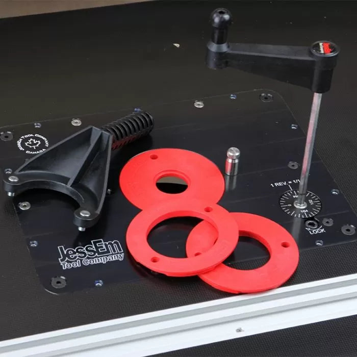 Router table plate with red insert rings, black handle, and adjustment tool for woodworking.