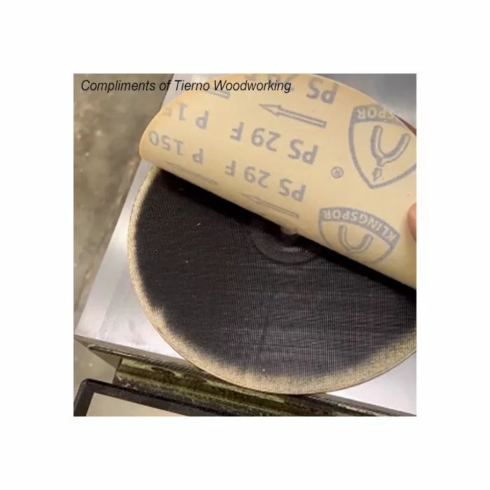 Close-up of sandpaper sheet being placed on a round sanding pad for woodworking