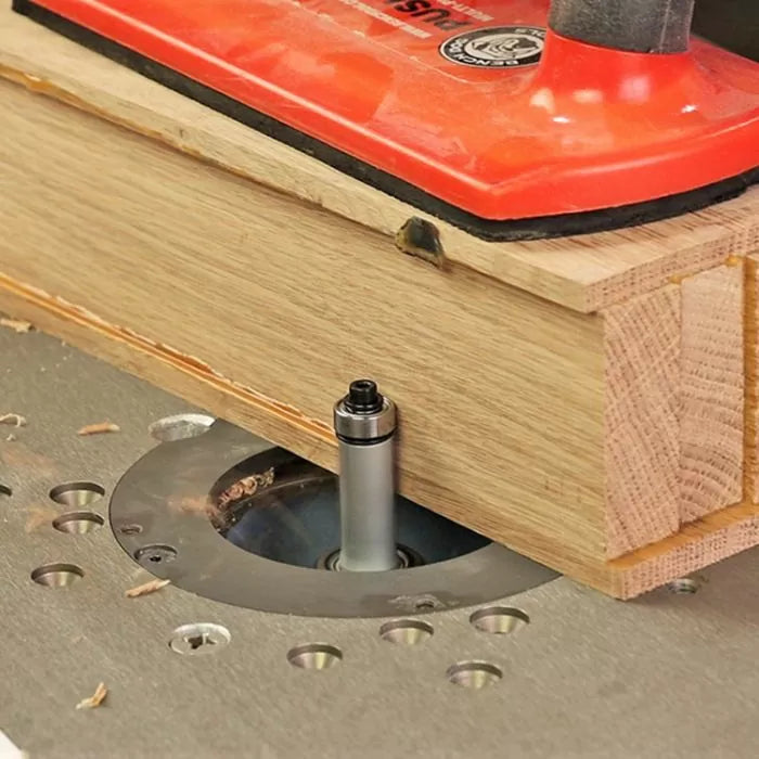 Straight router bit cutting wood on router table with push block for woodworking