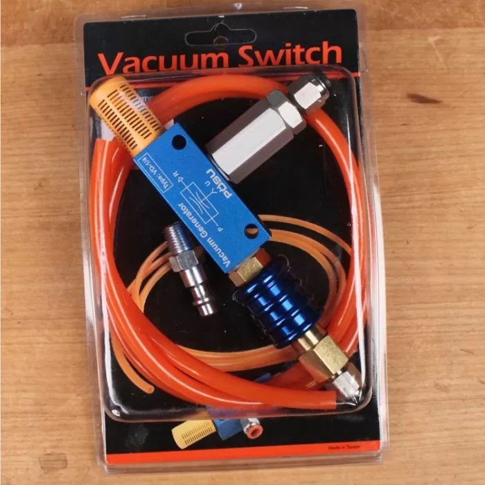 Vacuum switch kit with blue and silver components, orange tubing, and fittings on wood surface