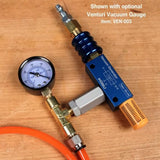 Venturi vacuum generator with attached vacuum gauge and orange hose on wooden surface
