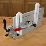 Woodworking tenoning jig with metal body, clamp, and adjustable handles on a workbench